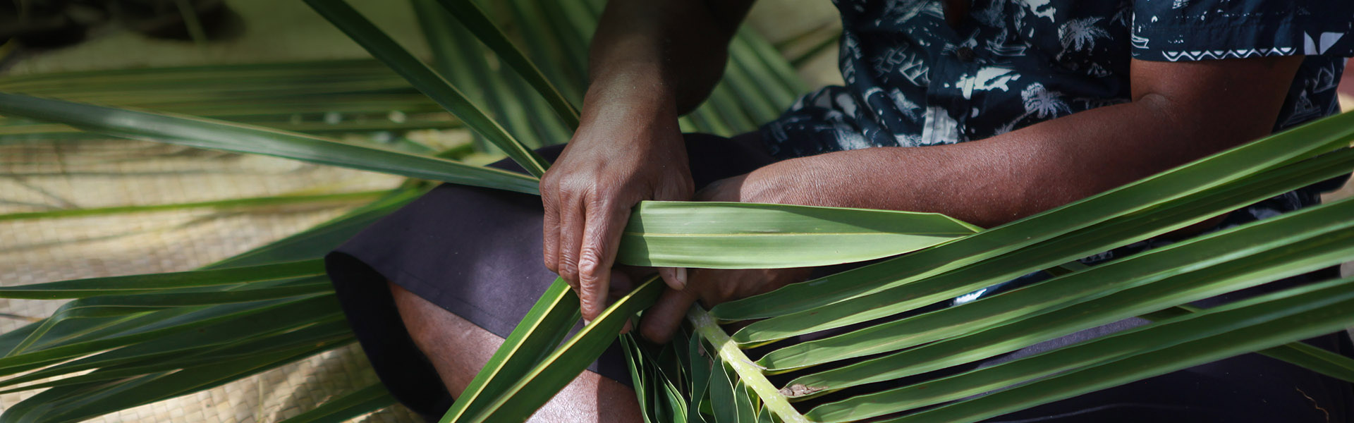 Hands weaving palm leaves together